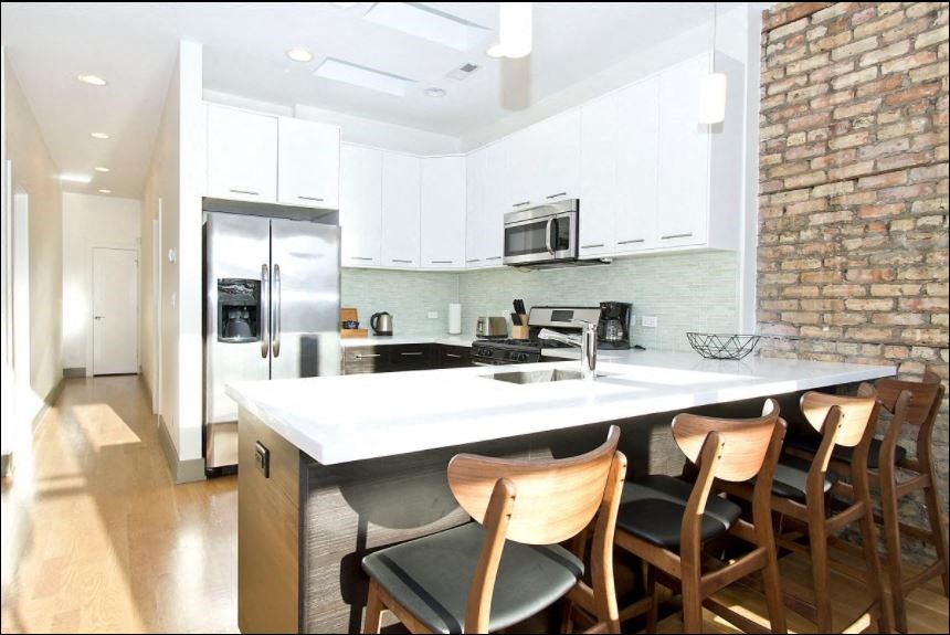 a large kitchen with a counter top and chairs