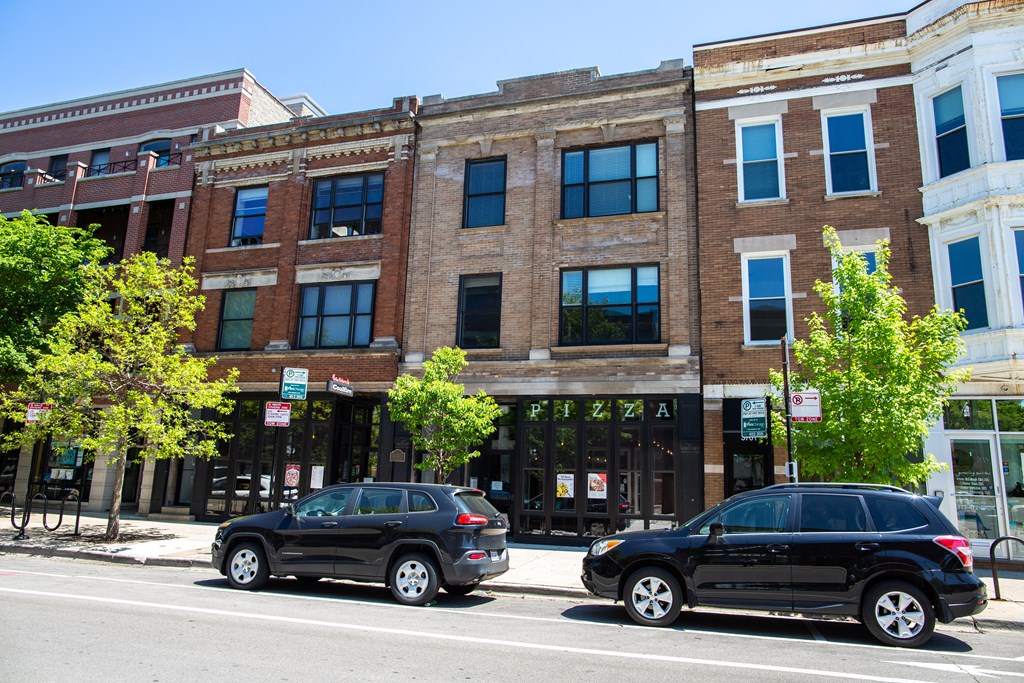 a city street with cars parked in front of a brick building