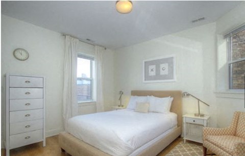 a white bedroom with a bed and a chair