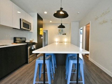 a modern kitchen with blue bar stools and a white counter top