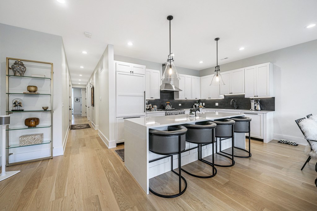 a white kitchen with a large island with four stools