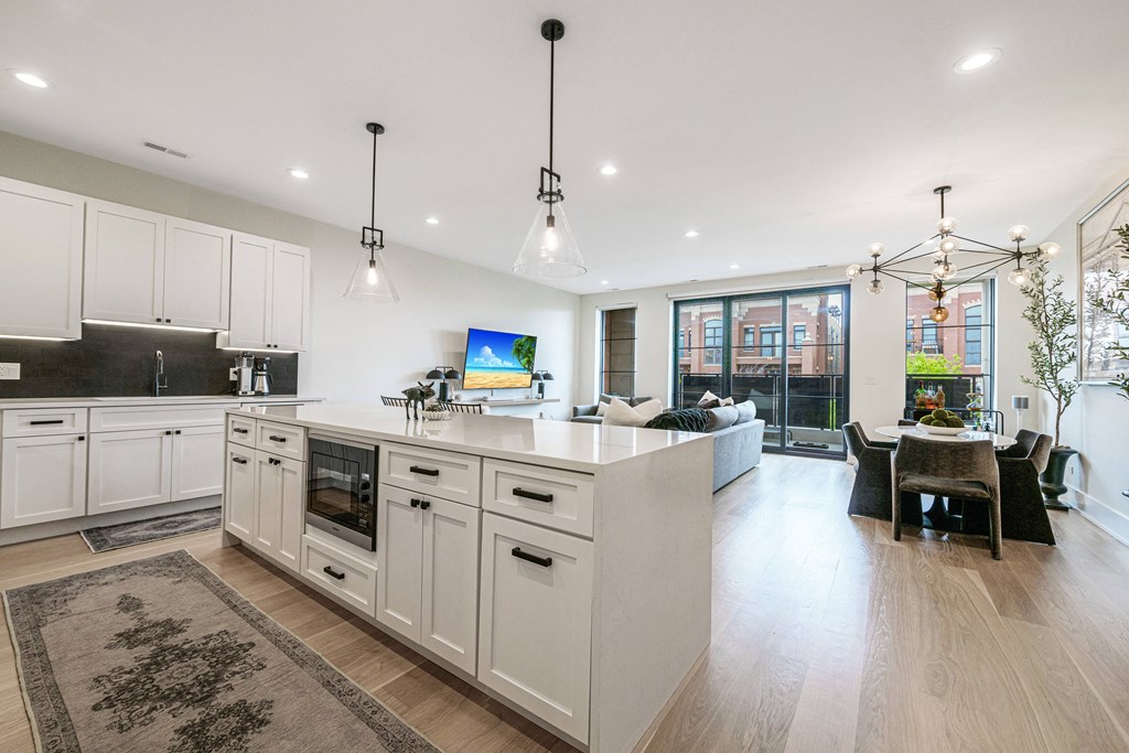 a large white kitchen with a large island and a living room
