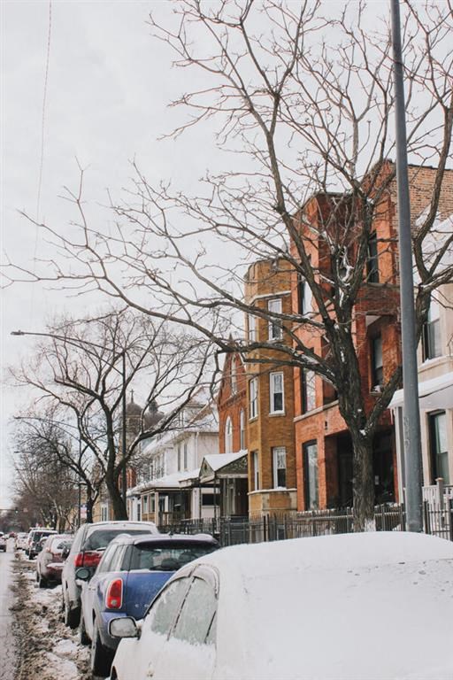 a city street with cars parked in the snow