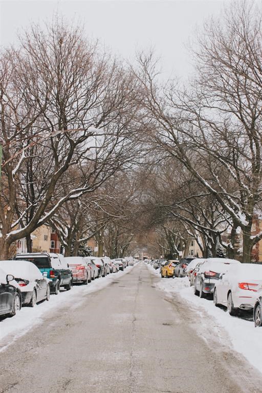 a snowy street with cars parked on the side of it