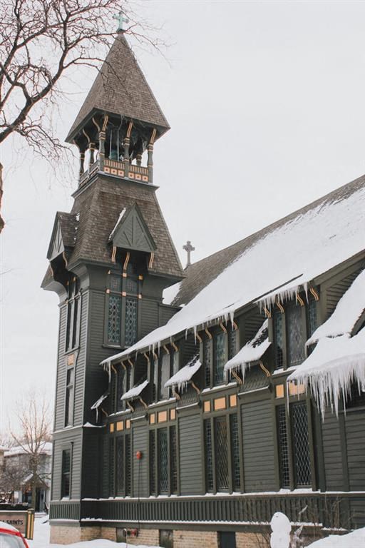 a church with a steeple and snow on the roof