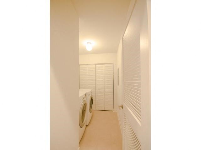 a white bathroom with a washing machine and a closet