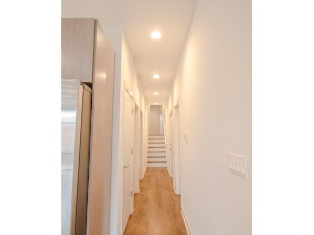 a hallway with white walls and a staircase  and a mirror
