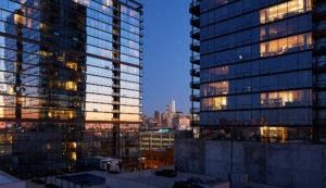 two tall glass buildings with a city skyline at night