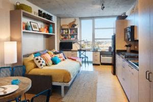 a living room with a bed and a kitchen