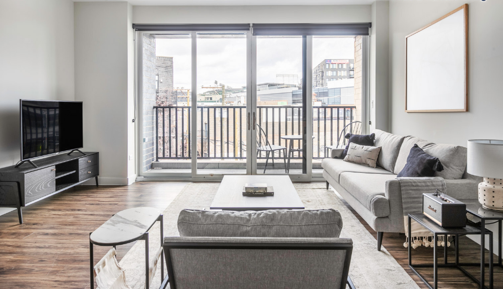 a living room with a couch and a tv and a balcony