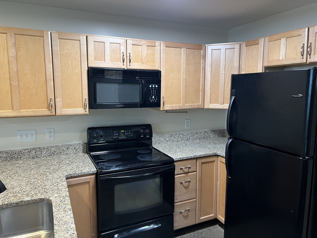 a kitchen with black appliances and wood cabinets