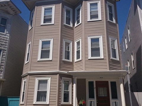 A brown house with a red door and windows.