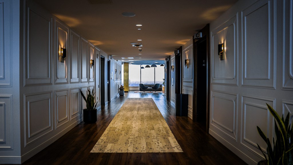 a hallway with wood floors and white walls and a rug