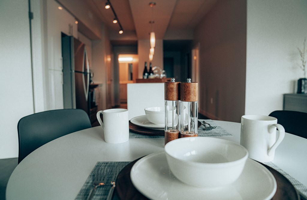 a dining table with a white table cloth and white plates and bowls