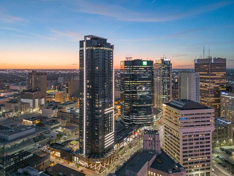A cityscape at dusk with buildings illuminated and a clear sky.