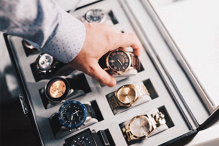 a man selecting a watch in a box of watches