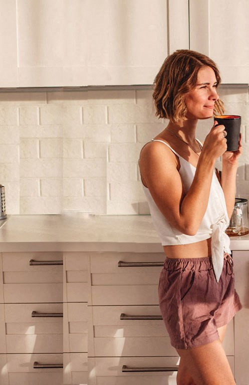 a woman standing in a kitchen with a cup of coffee