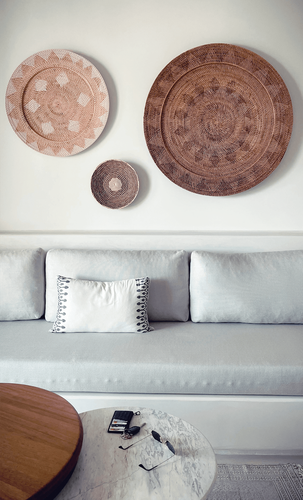 a living room with a sofa and wicker plates on the wall