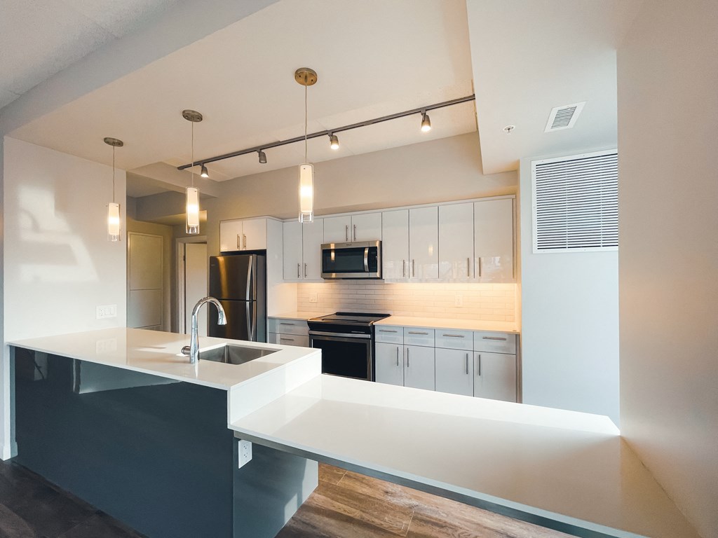 a kitchen with white cabinets and black appliances and a large counter top