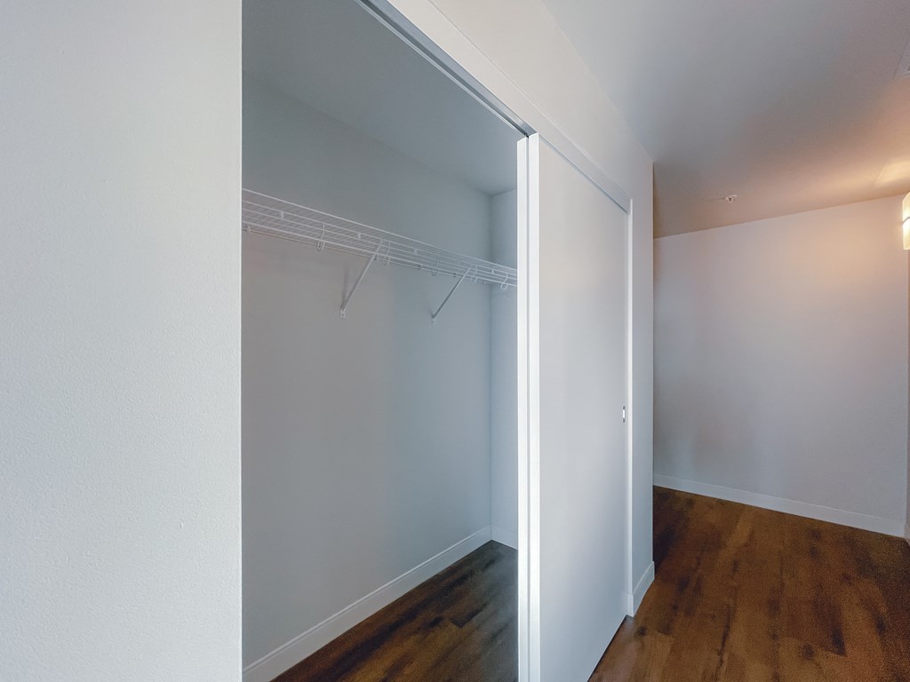 an empty room with a closet with a white wall and a wood floor