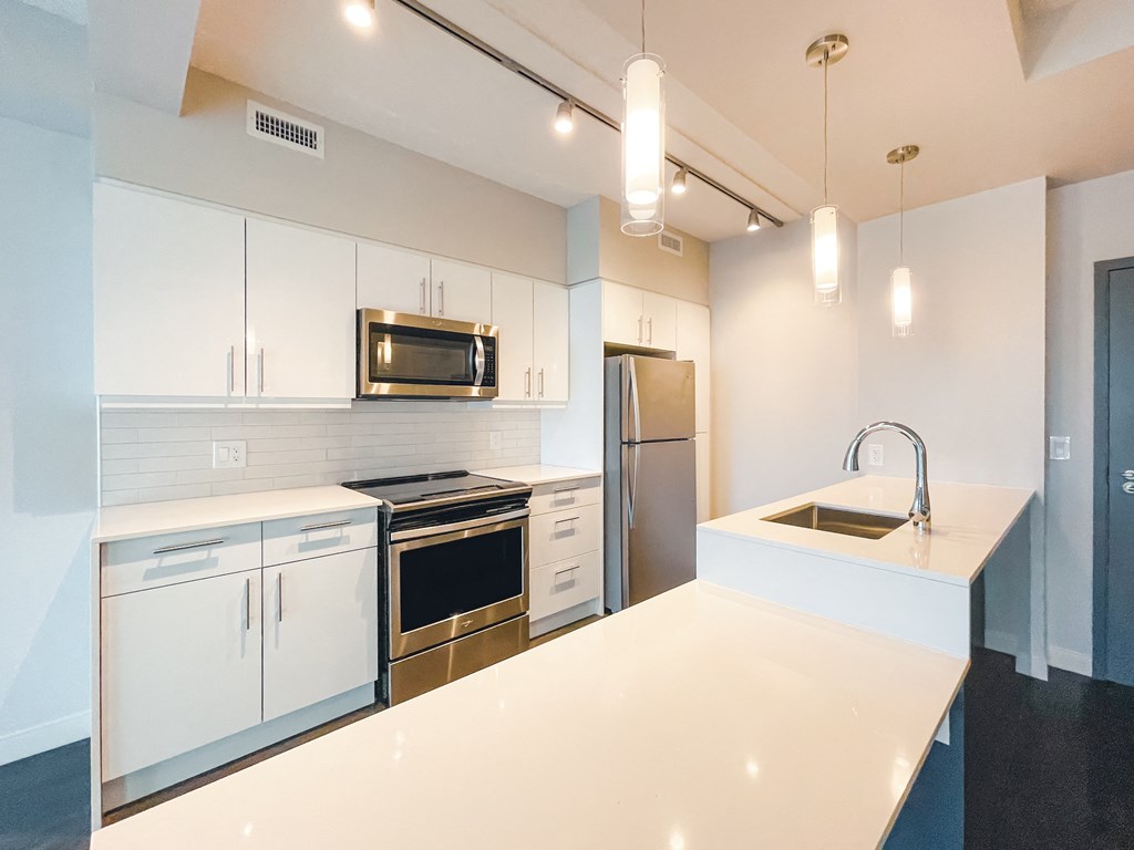 a kitchen with white counter tops and stainless steel appliances