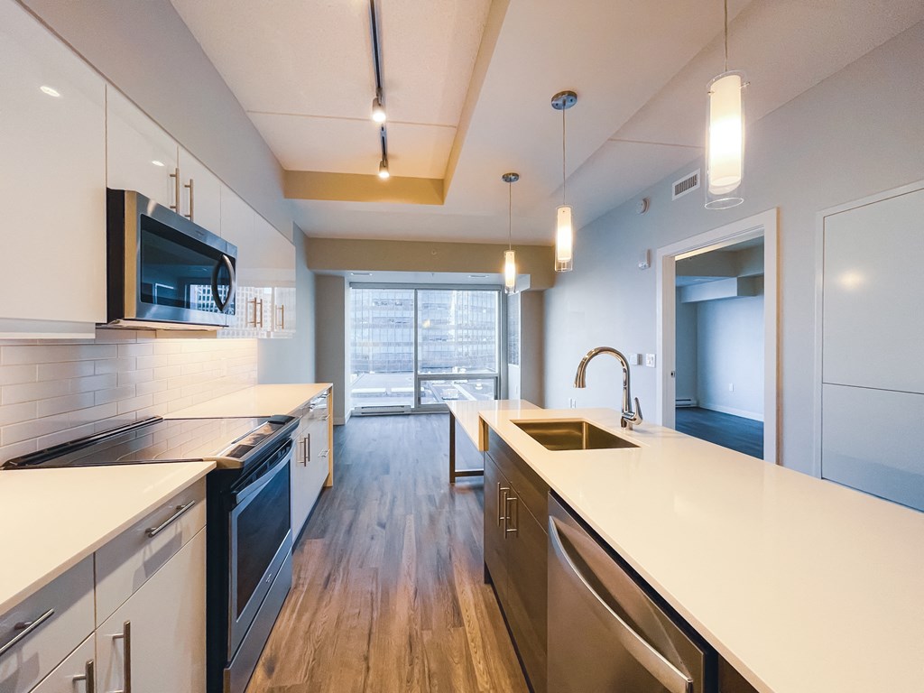 a large kitchen with white counter tops and a sink and a window
