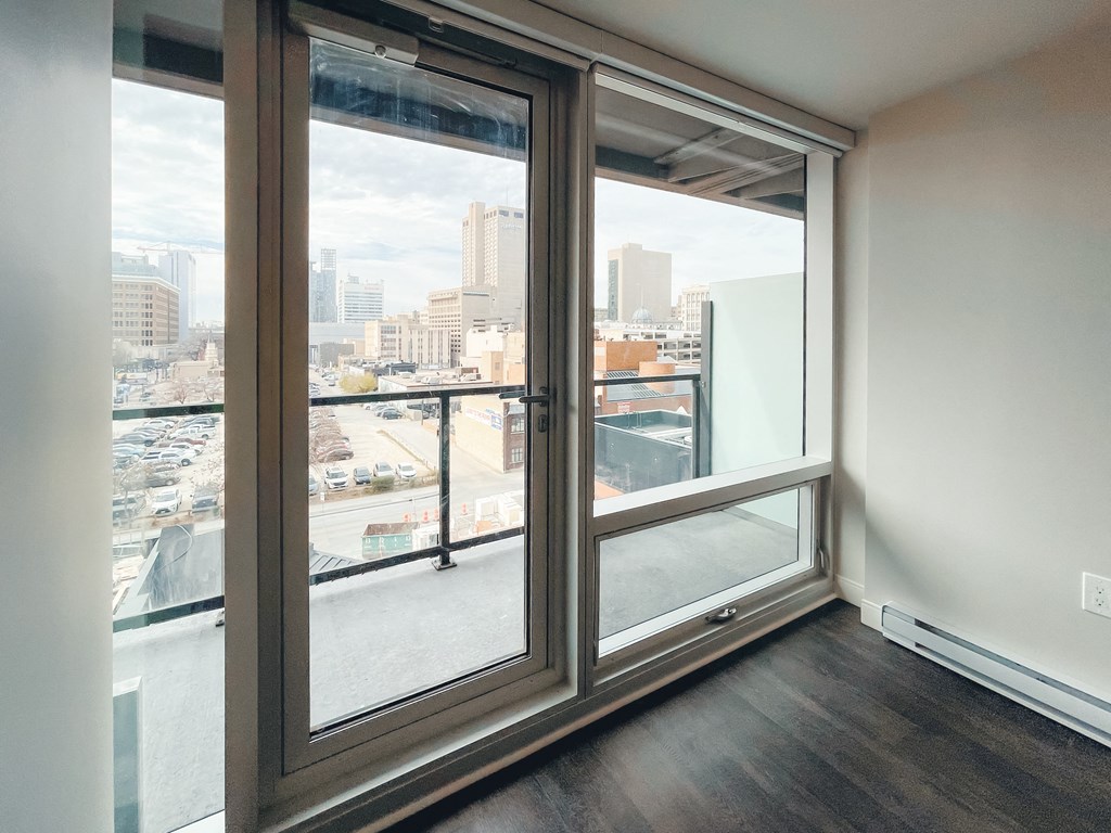 an empty living room with large windows and a city view