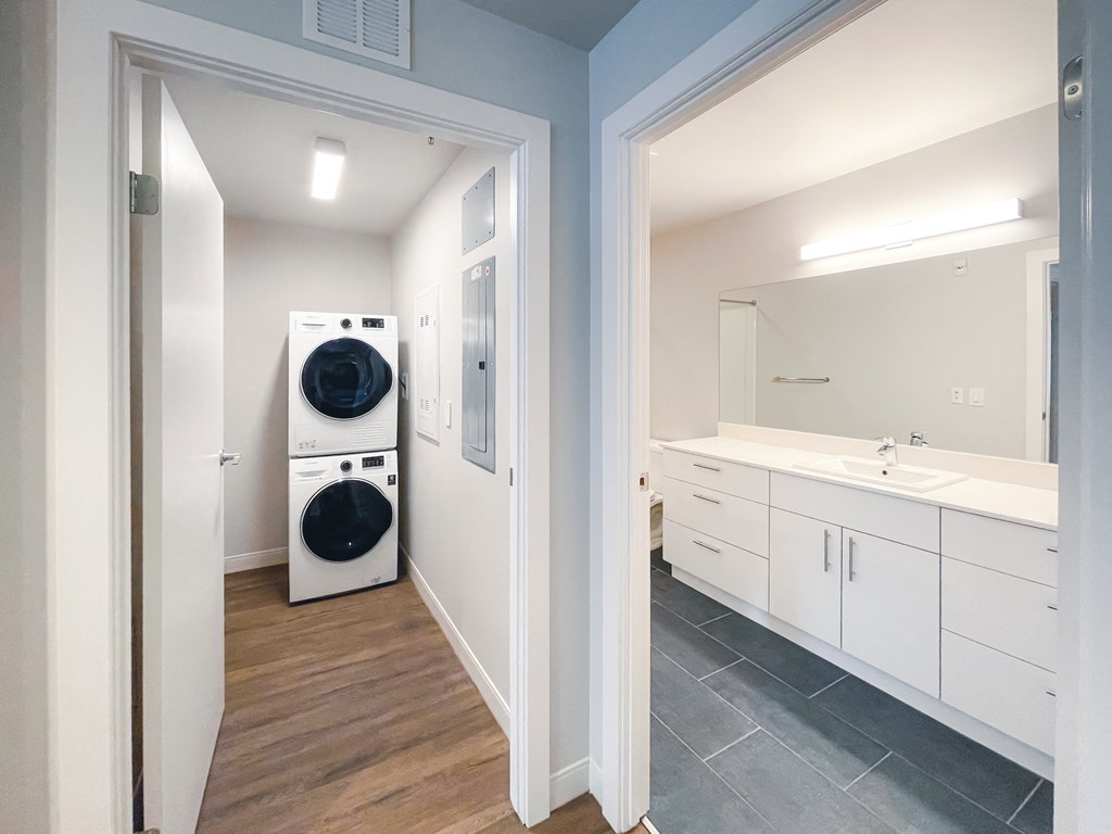 a washer and dryer in a laundry room with a sink and a mirror