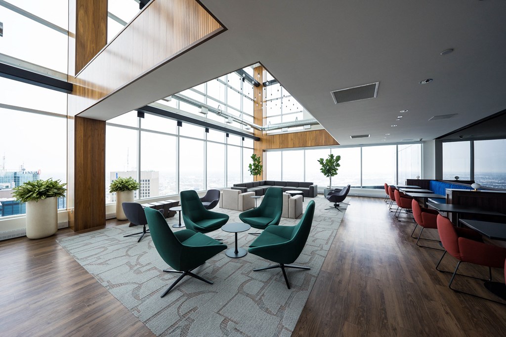 a lounge area with chairs and tables and floor to ceiling windows