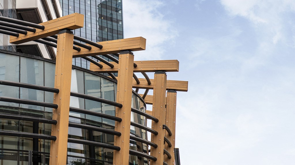 a close up of a building with wooden beams and a large glass building in the background