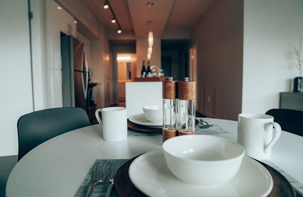 a dining table with a white table cloth and white plates and bowls