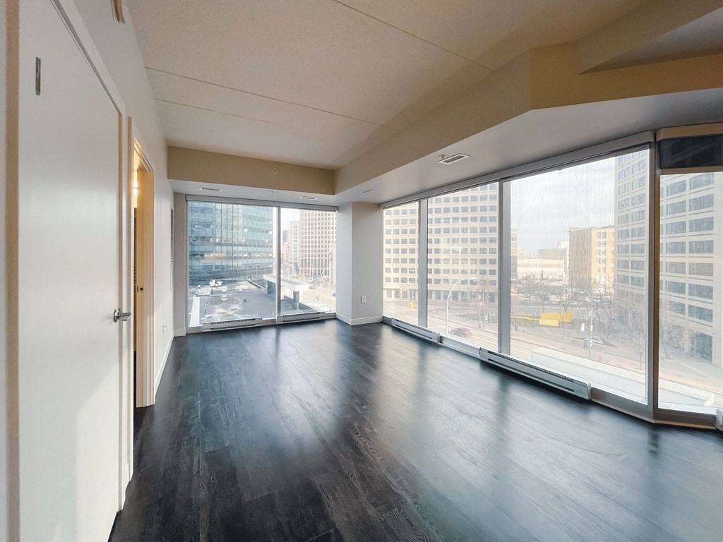 an empty living room with large windows and a view of the city