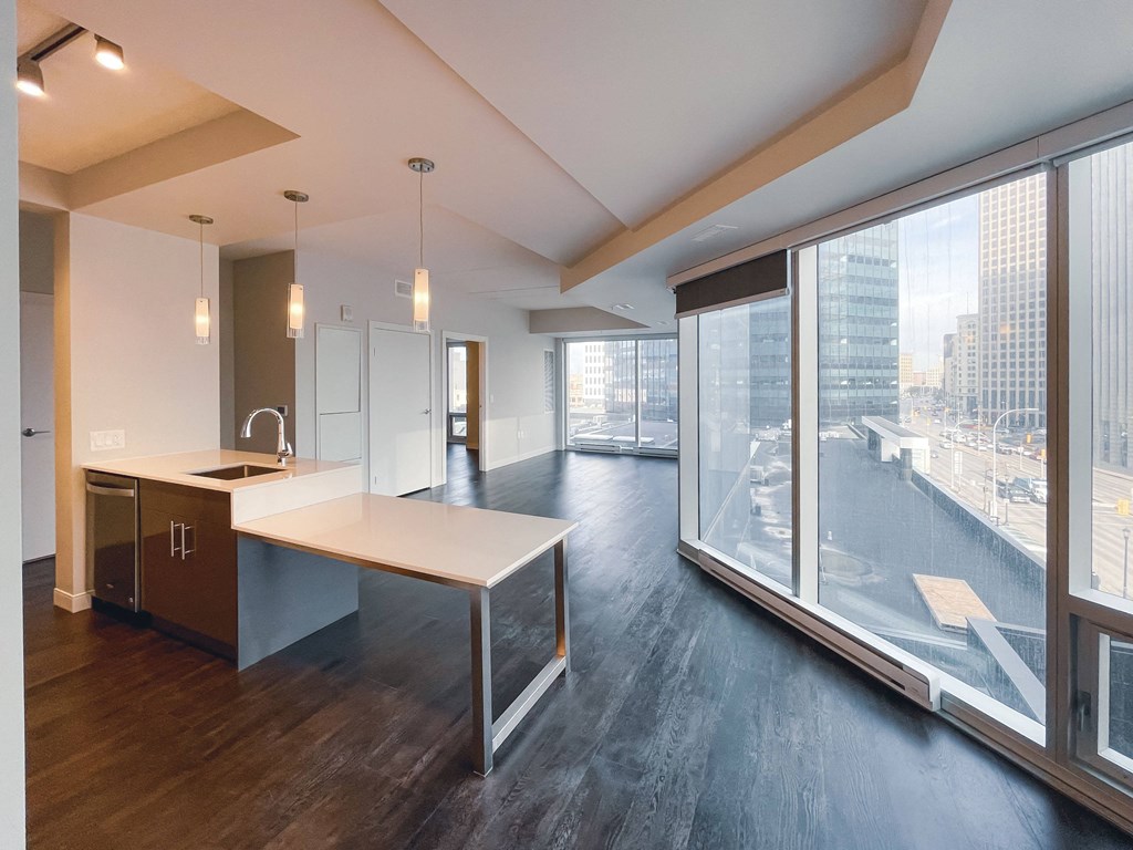 a kitchen and living room in an apartment with large windows and a view of the city