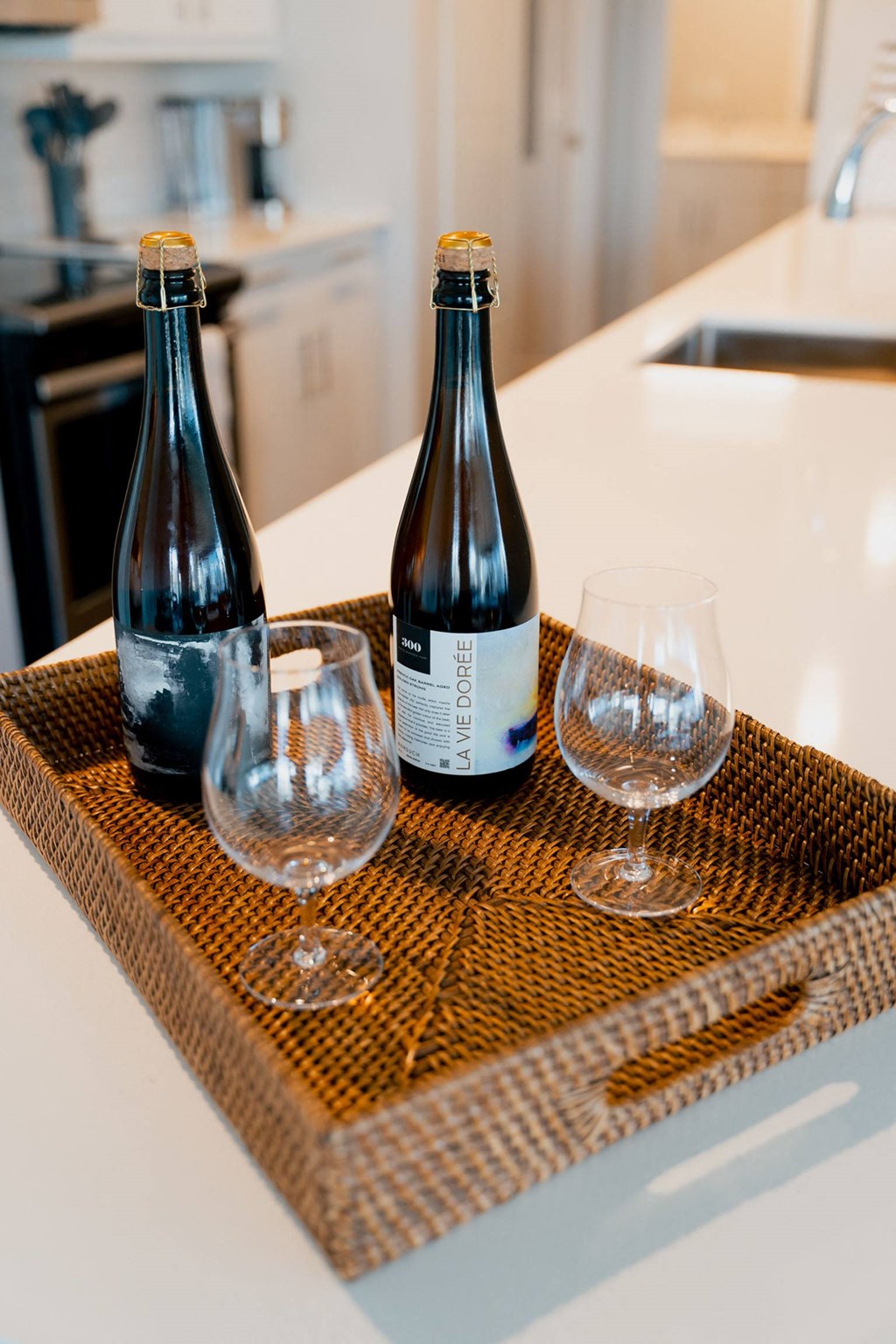 two bottles of wine and two glasses on a kitchen counter