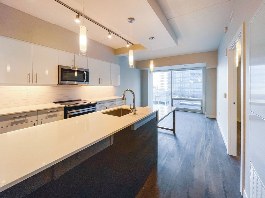 a kitchen with white countertops and a large window