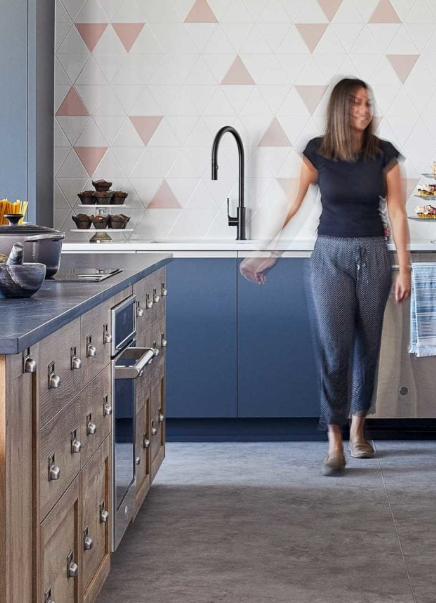 a woman walking in a kitchen with a sink