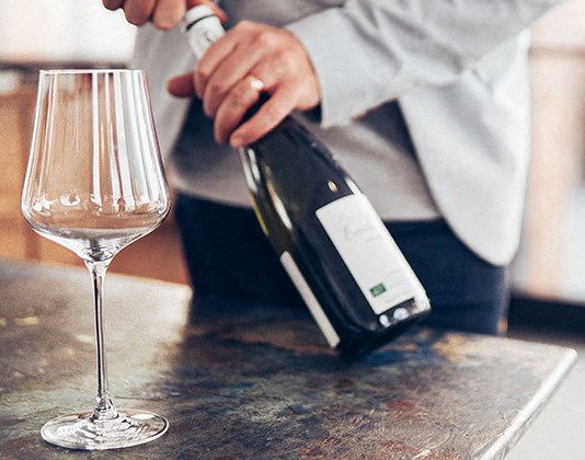 a person pouring a glass of wine into a wine glass