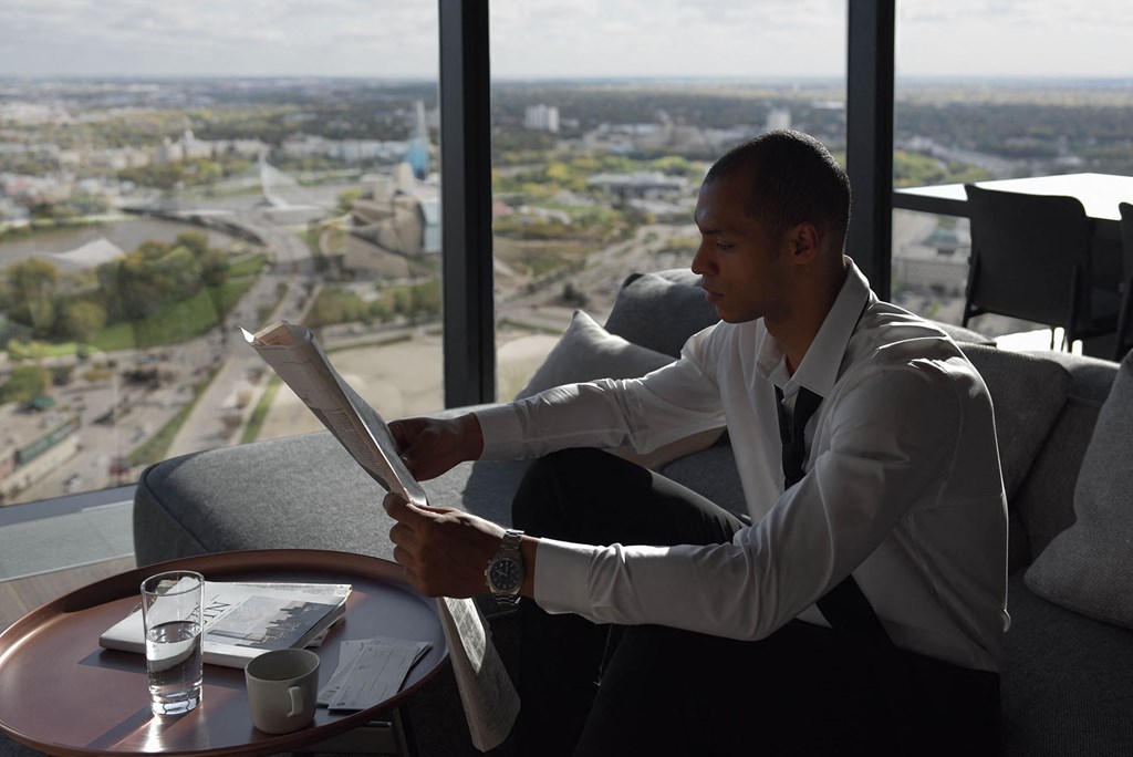 a man sitting in a chair looking at a laptop computer in a window