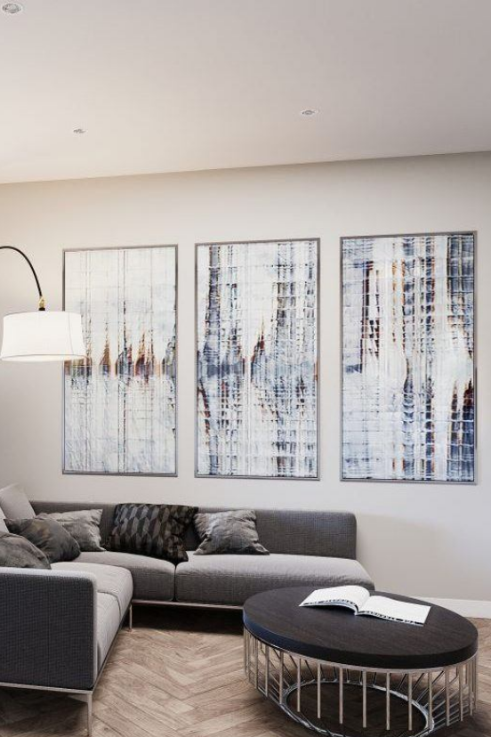 a living room with a couch and three paintings on the wall