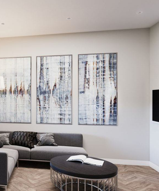 a living room with a couch and three paintings on the wall