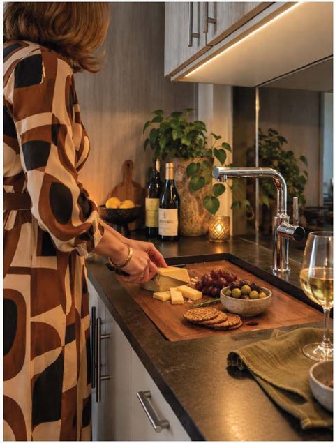 A woman in a patterned dress is preparing food in a modern kitchen.