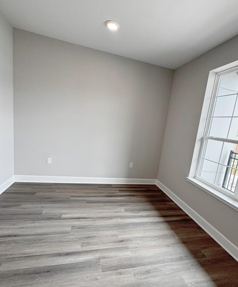A room with a window and a wooden floor.