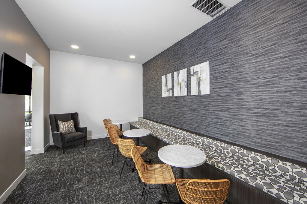 a lounge area with tables and chairs in a room with a tv