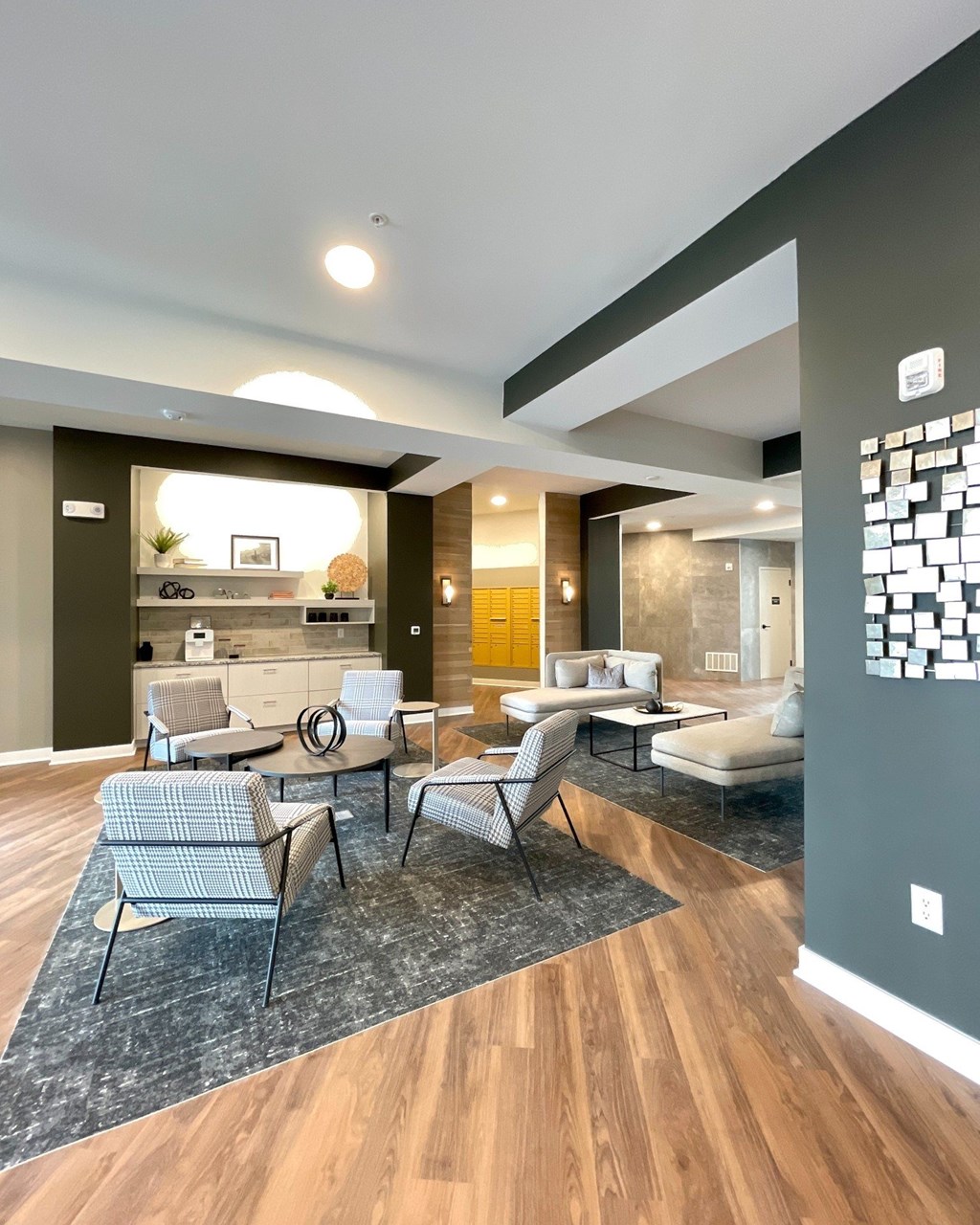 A modern living room with a grey sofa and a grey and white checkered chair.