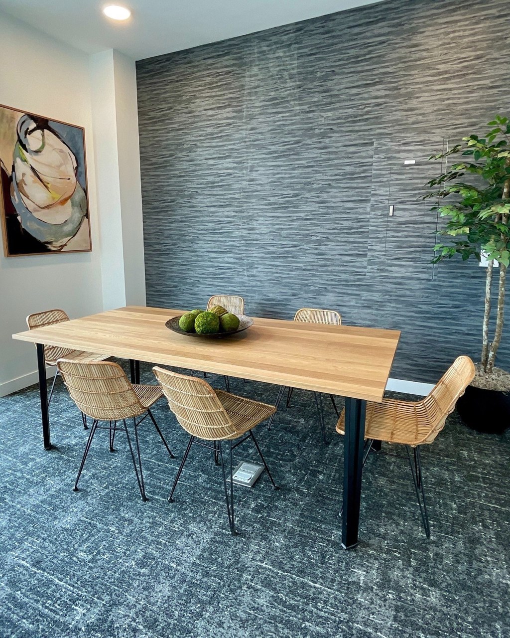 A dining table with chairs and a bowl of fruit on it.