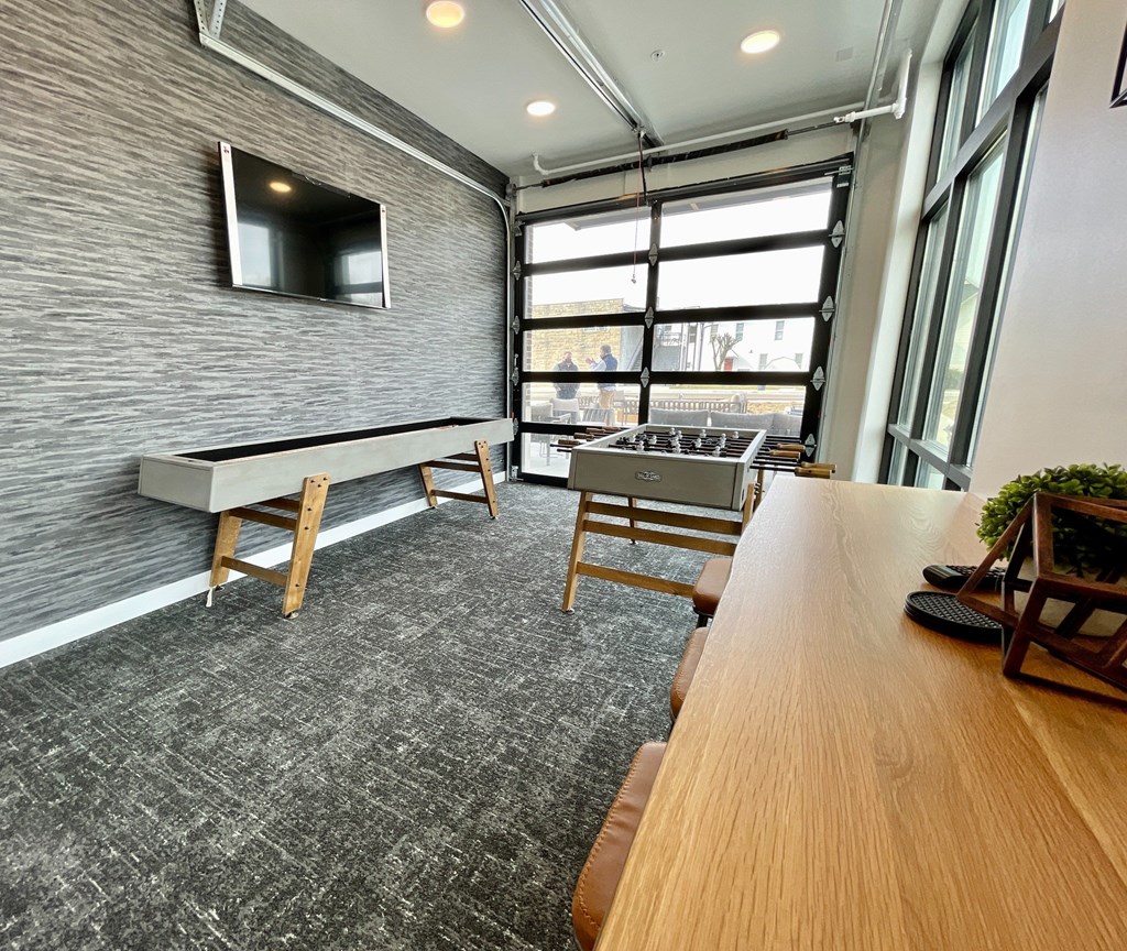 A room with a long wooden table and a television mounted on the wall.