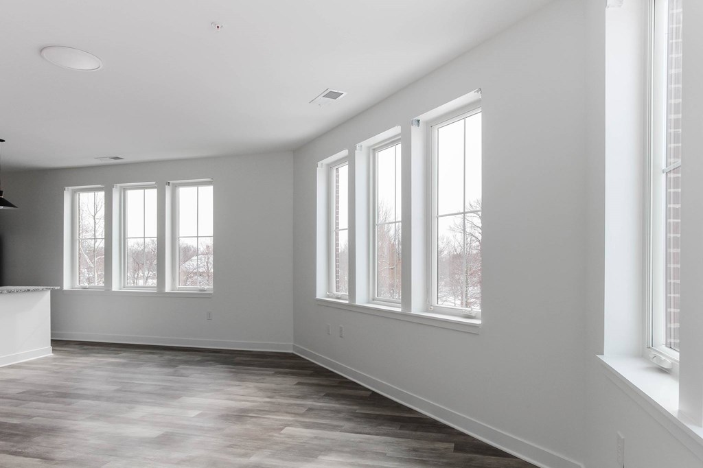 A large empty room with a fireplace and windows.