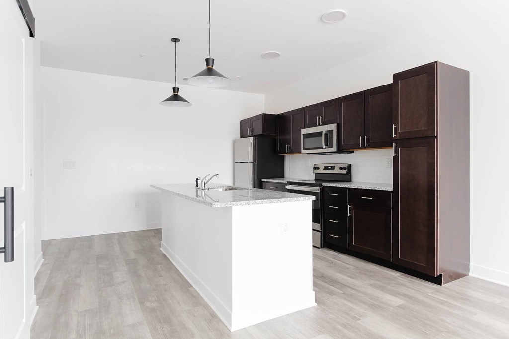 A kitchen with a white island and dark brown cabinets.