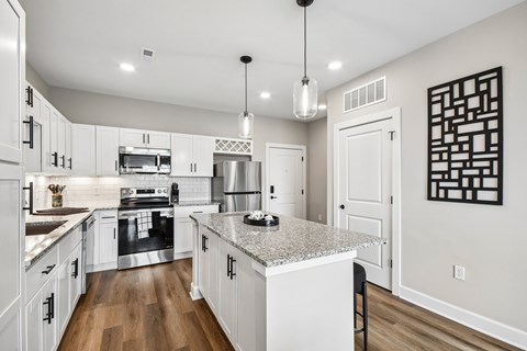 A modern kitchen with white cabinets and a granite countertop.