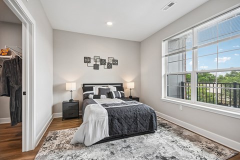 A bedroom with a large bed and a window overlooking a fence.
